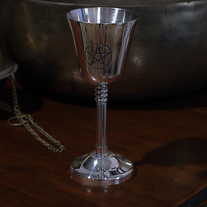 Silver goblet with pentagram design on a wooden surface