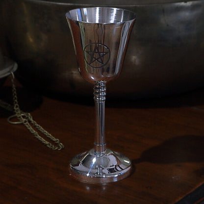 Silver goblet with pentagram design on a wooden surface