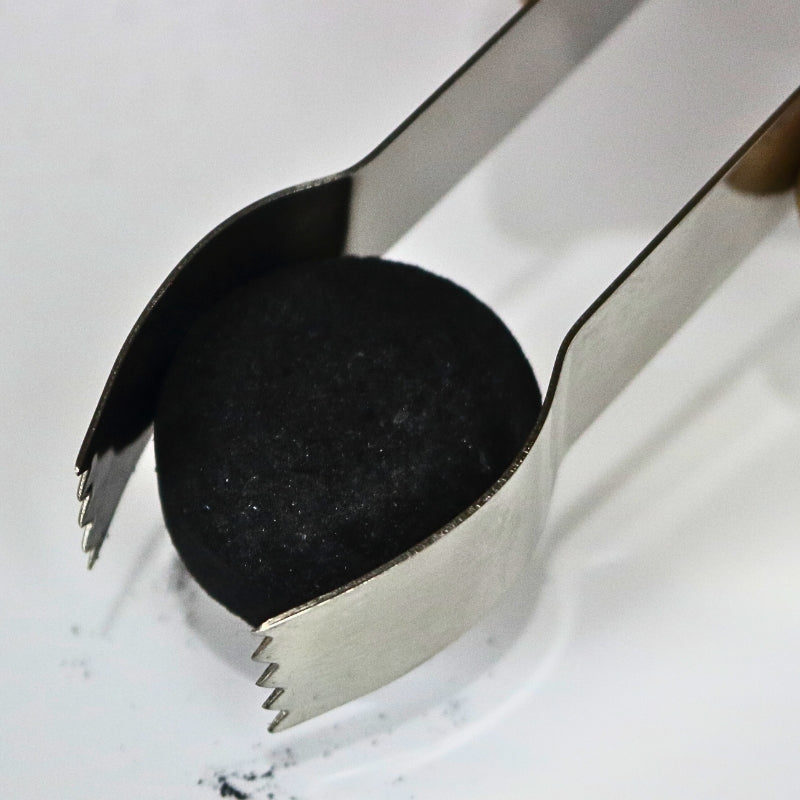 stainless steel charcoal tongs holding a charcoal tablet