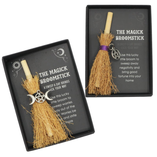 Two small broomsticks in black display boxes labeled "The Magick Broomstick." Each broomstick is tied with a string and adorned with a charm featuring a pentagram and crescent moons. 