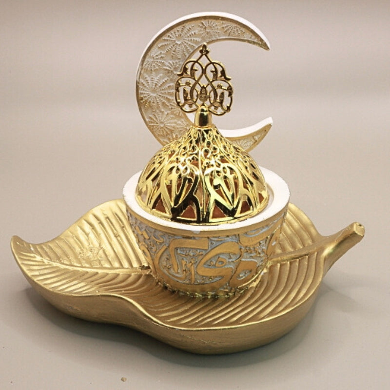 white and gold incense burner in the shape of a crescent moon on a gold leaf