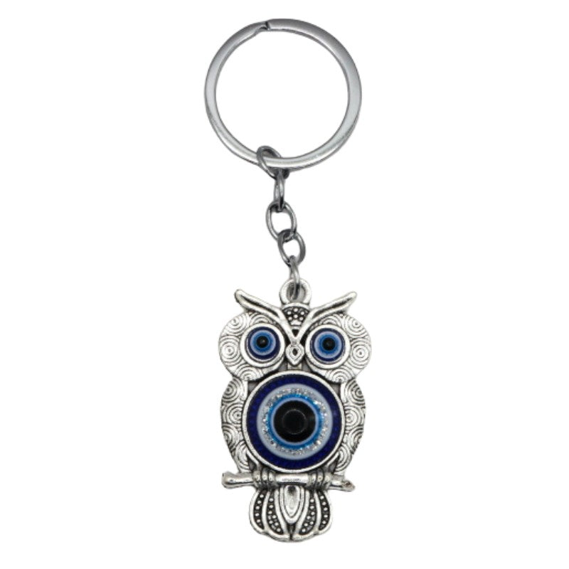 silver coloured metal keyring in the shape of an owl with a blue and white eye in the centre