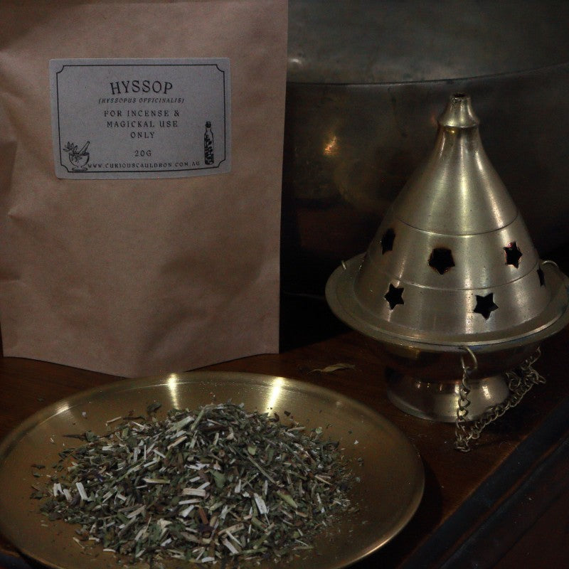 Incense herbs on a plate with a metal cone incense burner and a labeled bag in the background.