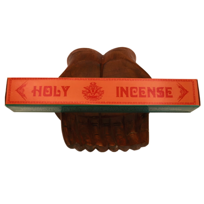 pk of hand rolled "Holy Incense" tibetan incense sitting on a statue of carved wooden hands