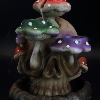 backflow incense cone burner of a skull with colourful mushrooms growing out the side of it, with incense smoke flowing down the mushrooms.