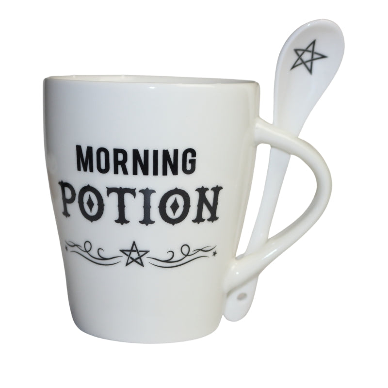 White ceramic coffee mug with the phrase "morning potion" written in black above a pentagram. A white spoon through the mug handle with a black pentagram drawn in the bowl of the spoon
