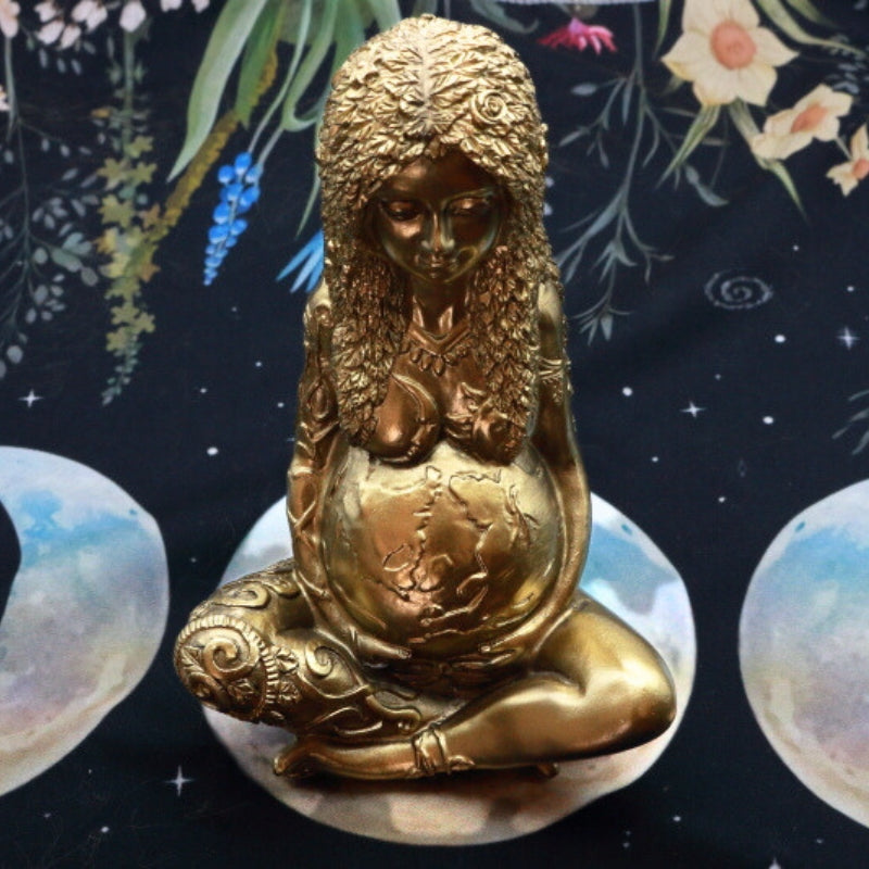 gold statue of a woman with the earth as her pregnant stomach representing mother earth on an altar cloth