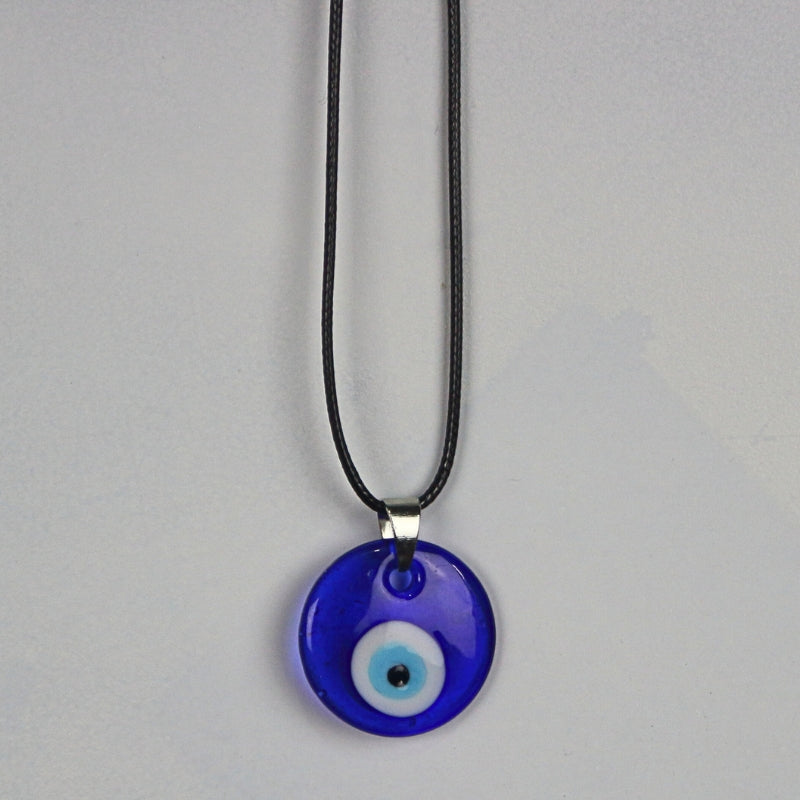 blue, white, light blue and black concentric circles  formed into an eye shaped bead, hung on a black cord with a silver clasp. The necklace hangs on a light grey wall