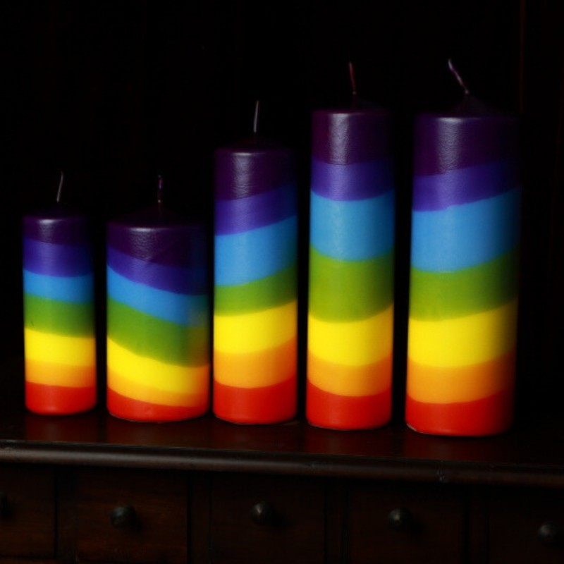 5 rainbow pillar candles on a wooden apothecary chest