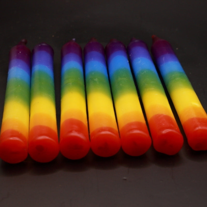 rainbow coloured candles laid out in a row of 7