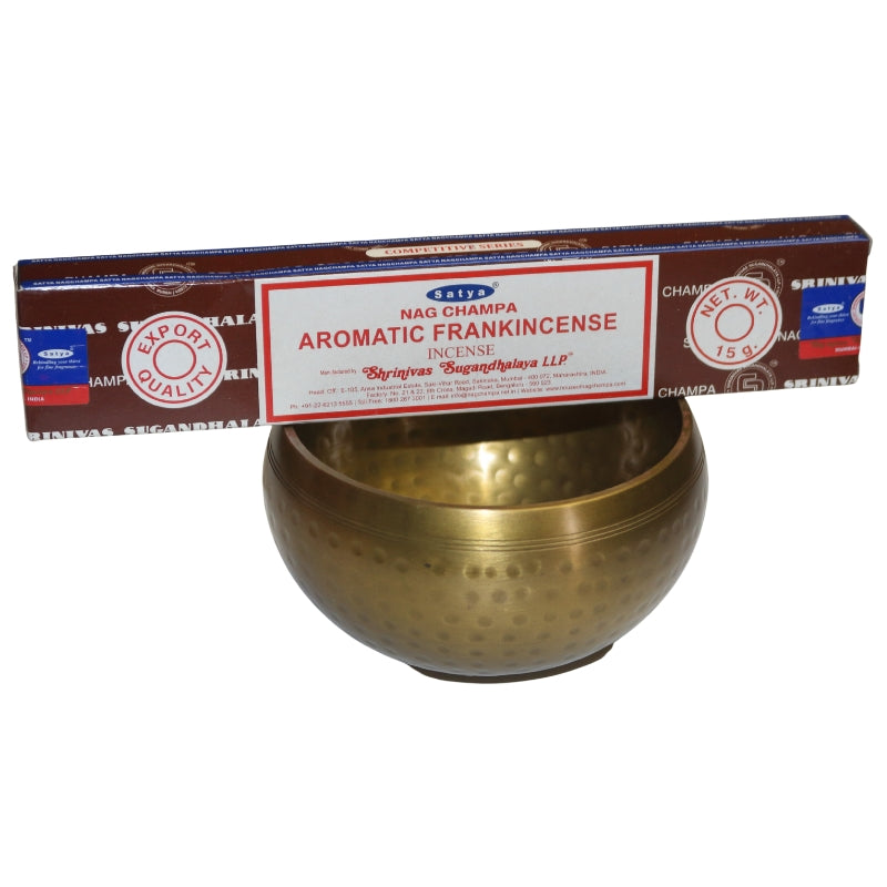 brown and white rectangulat box of satya aromatic frankincense incense sitting on a brass singing bowl