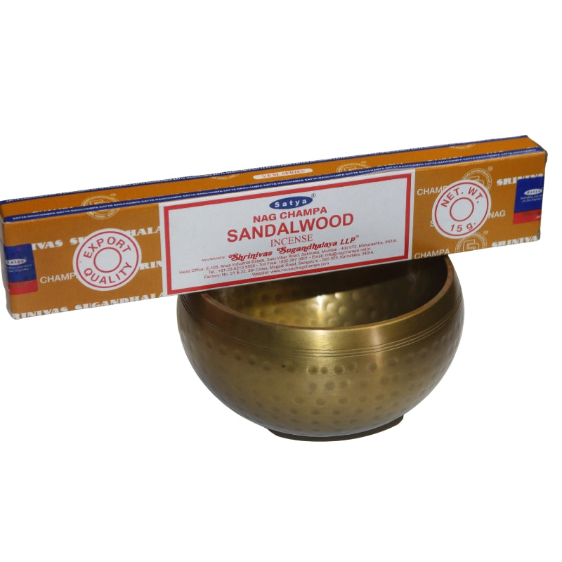 tan and white coloured box of satya sandalwood incense sitting on top of a brass singing bowl