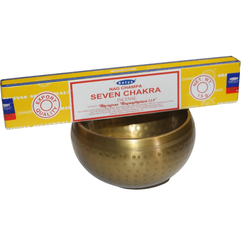 yellow incense box of satya seven chakra incense sitting on a brass singing bowl