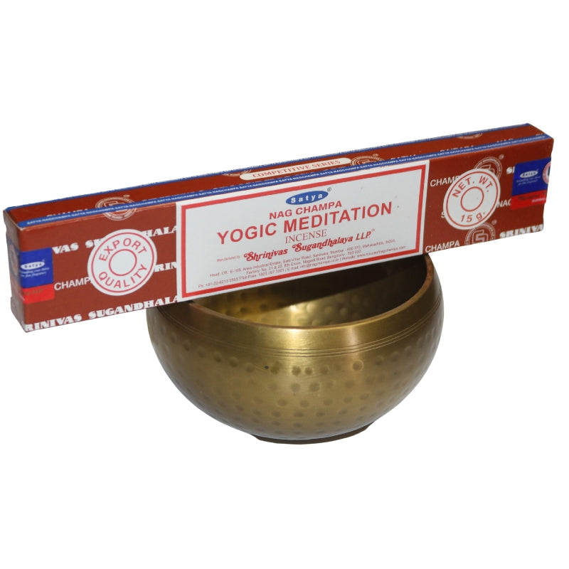 brown and white box of Yogic meditation incense sitting on a brass singing bowl