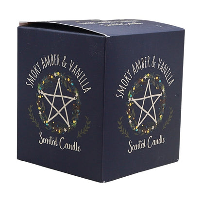 A dark navy blue square cardboard box for a scented candle, featuring a white pentagram inside a floral wreath with the text 'SMOKY AMBER & VANILLA' and 'Scented Candle'.
