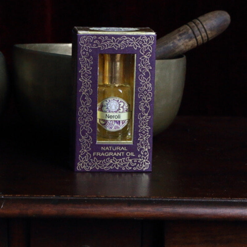 song of india neroli perfume oil in front of a brass singing bowl on an apothecary cabinet