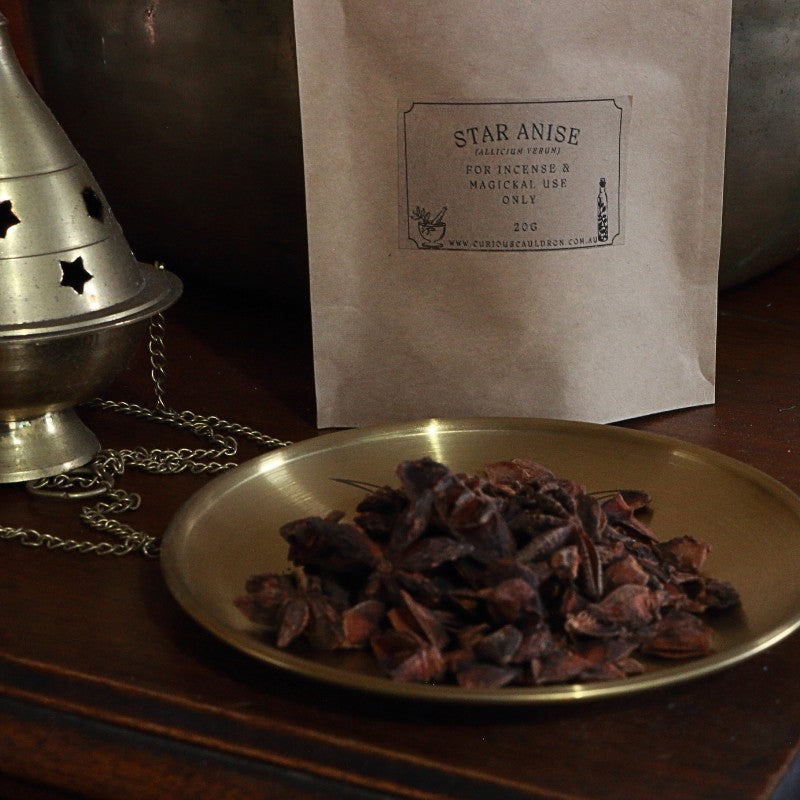 Star anise on a brass plate with a labeled brown bag in the background