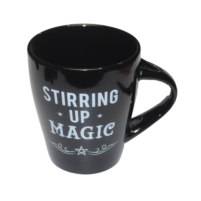 black mug decorated with the words "stirring up magic "  written in white