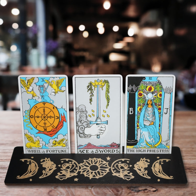 3 tarot cards in a black tarot card holder on a table 