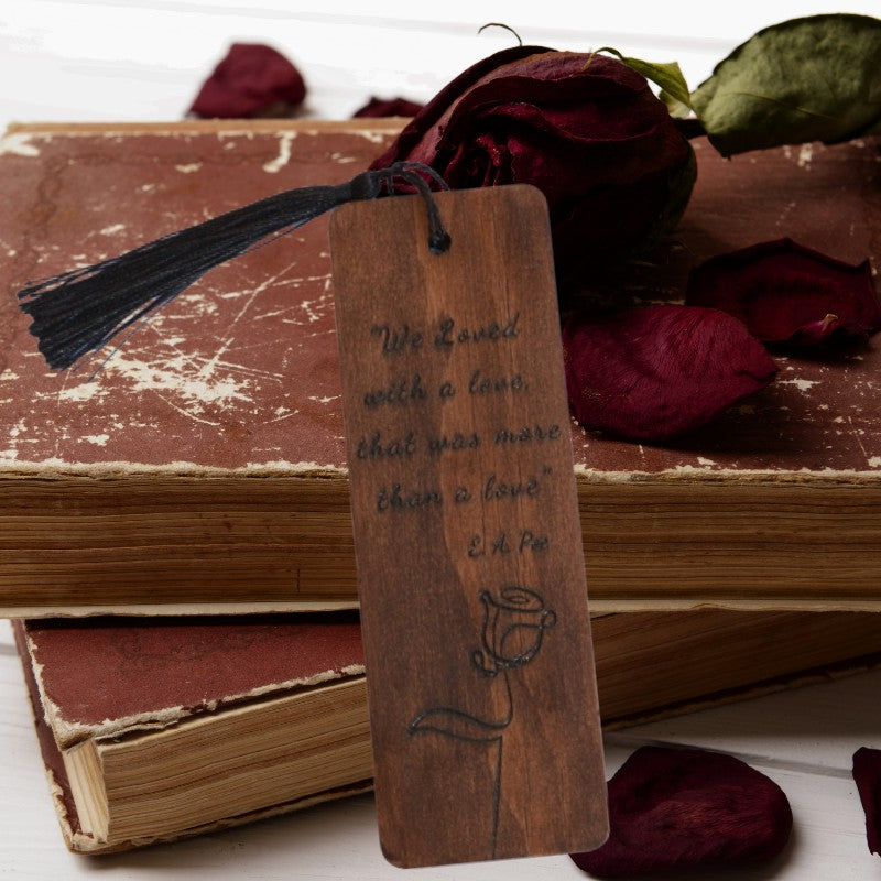 handmade bookmark leaning against old books with a dried red rose