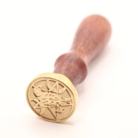 Brass wax seal stamp with a raven and triple moon pentacle design on a wooden handle