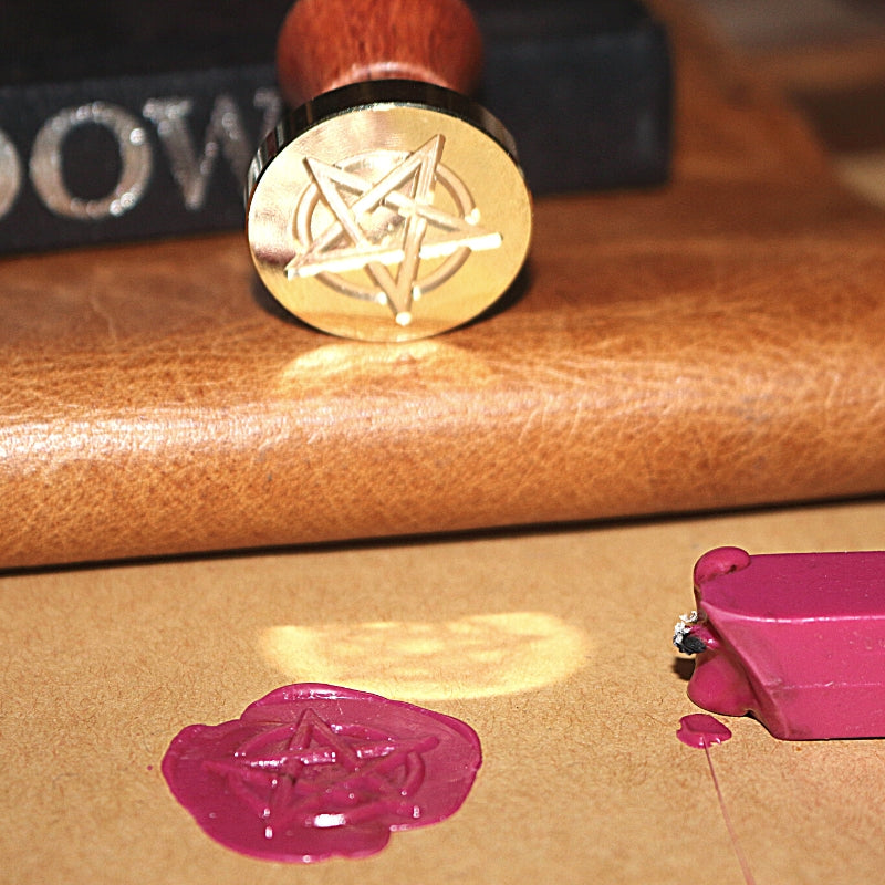 pentagram wax seal stamp on a leather journal with a pink wax seal and sealing wax