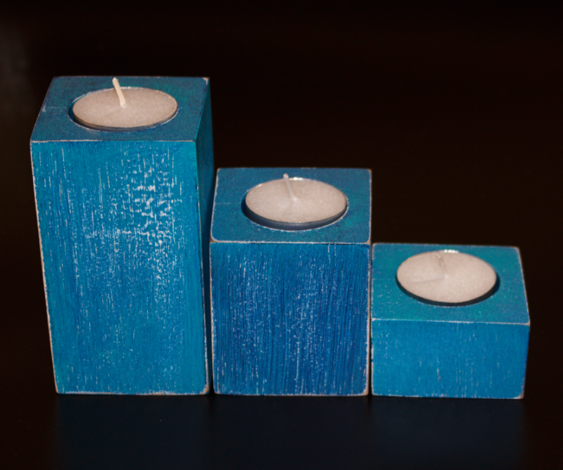 3 blue distressed square candles holding white tea lights, on a black background