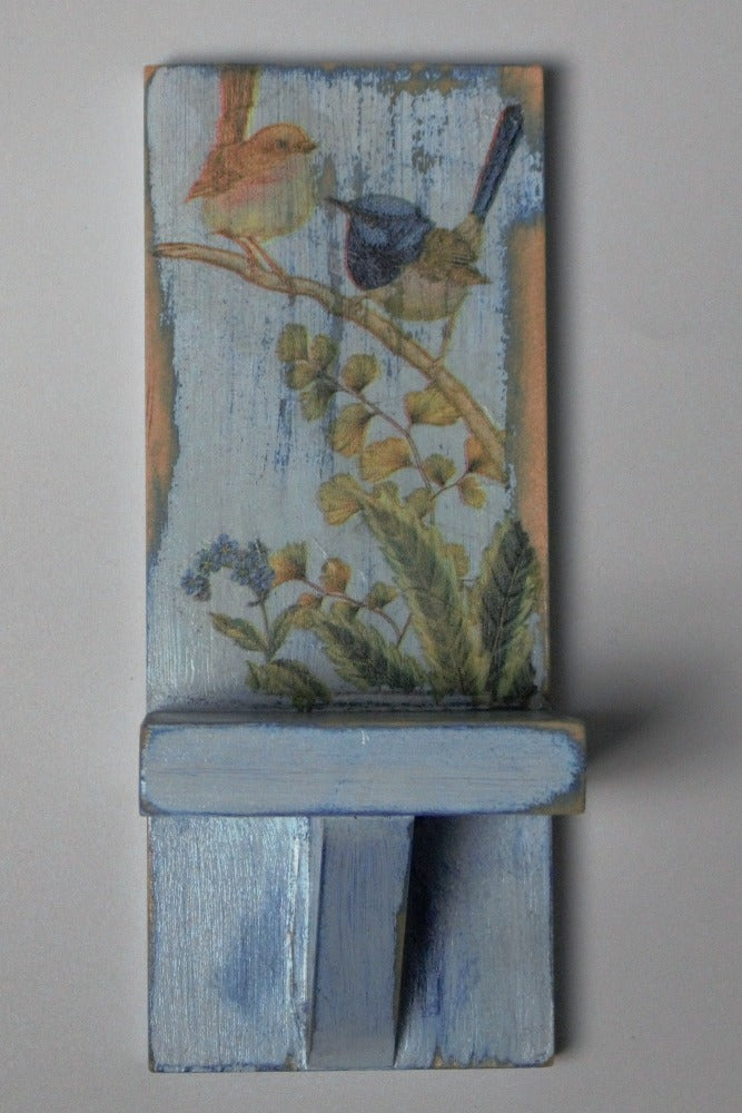 distressed blue and white wooden wall mounted candle or ornament shelf decorated with vintage style brown and blue wrens sitting on a branch with green ferns and blue flowers