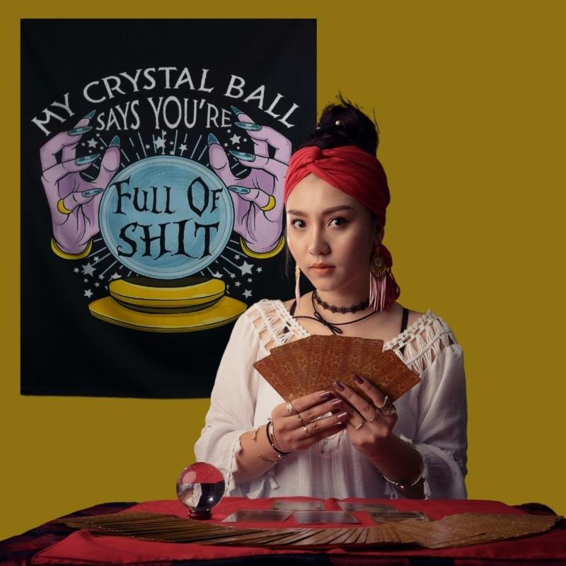 Tarot card reader standing at her desk with a crystal ball in front of a sign that had a picture of a crystal ball and hands which reads- my crystal ball says you're full of shit