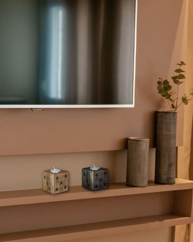 dark and light wooden square dice candle with white tea light candle on a shelf under a tv