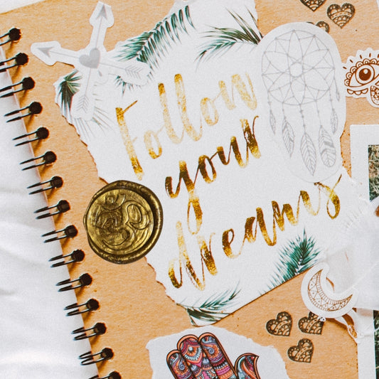 gold om wax seal on a scrapbook journal that says "follow your dreams"