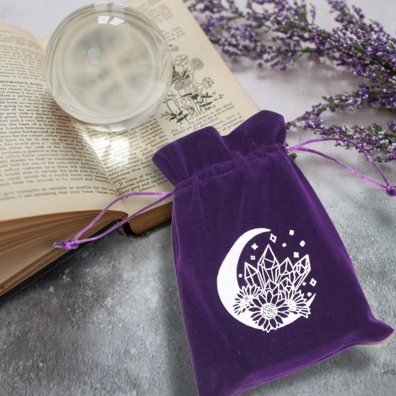 purple tarot bag with white moon and crystal print on open book with crystal ball and lavender flowers