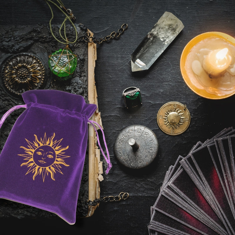 purple tarot bagon a table with tarot cards, clear quartz crystal, amulets and a candle