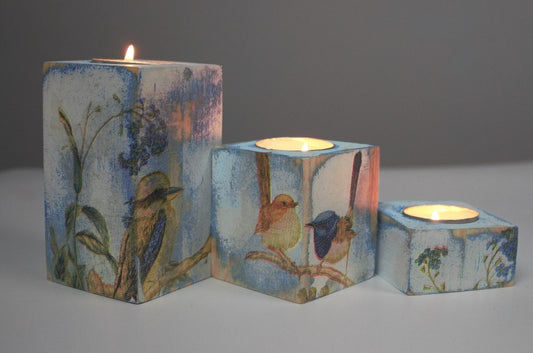 blue and white distressed set of 3 candle holders with lit tea light candles, decorated with a kookaburra, fairy wrens and blue flowers