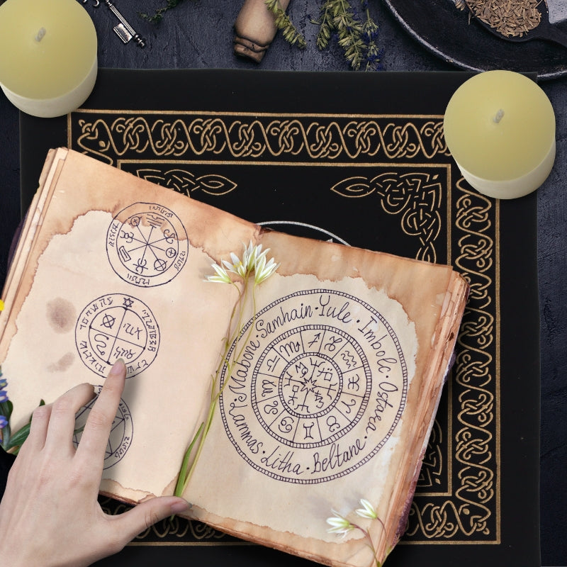 wiccan pointing to magic symbols in an old book  surrounded by beeswax pillar candles on a black and gold tarot cloth