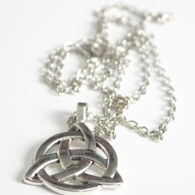 silver coloured triquetra necklace on a white background